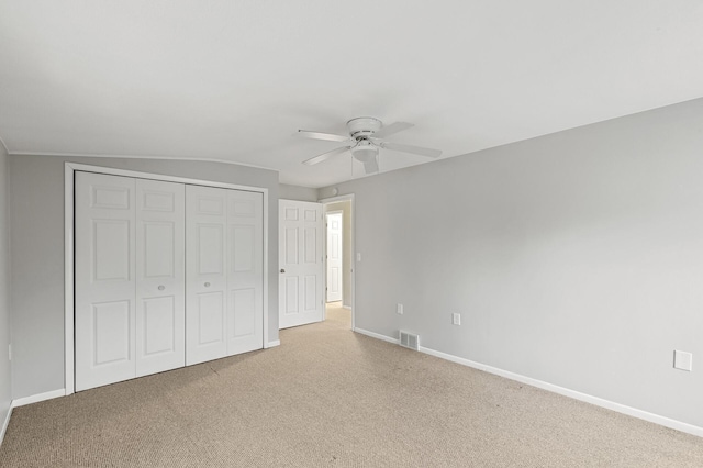 unfurnished bedroom with lofted ceiling, light carpet, ceiling fan, and a closet