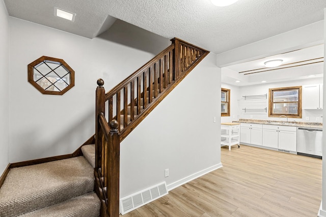 stairway with hardwood / wood-style flooring, sink, and a textured ceiling