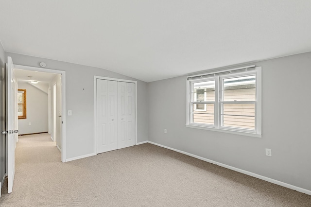 unfurnished bedroom with lofted ceiling, light colored carpet, and a closet