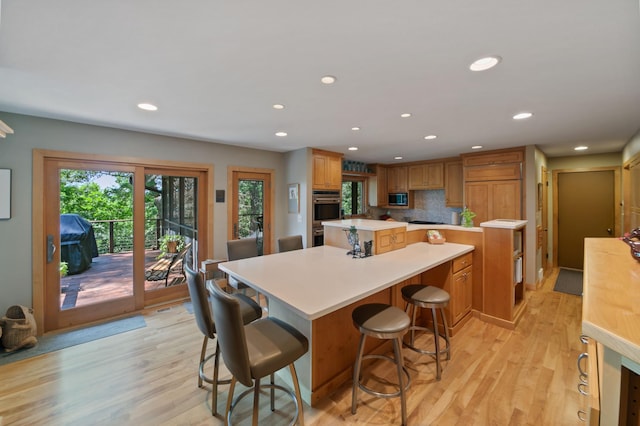 kitchen featuring a large island, tasteful backsplash, a kitchen breakfast bar, appliances with stainless steel finishes, and light wood-type flooring