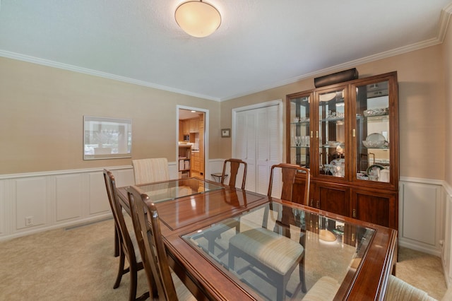 carpeted dining space with ornamental molding