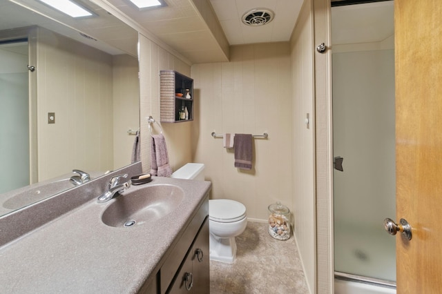 bathroom featuring toilet, vanity, and a shower with door