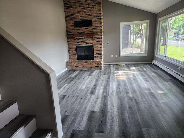 unfurnished living room with lofted ceiling, a fireplace, stairway, and wood finished floors