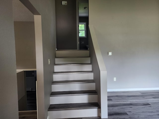 staircase with baseboards and wood finished floors