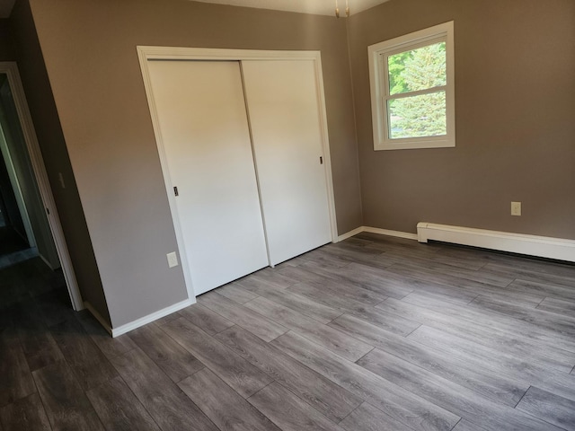 unfurnished bedroom with baseboards, dark wood finished floors, and a closet