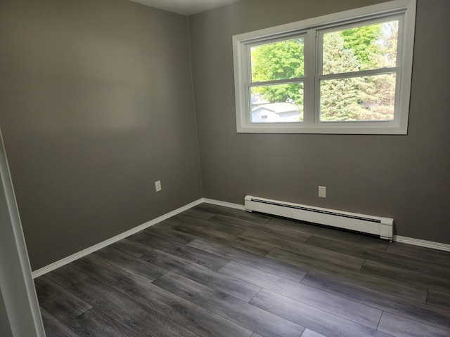 empty room with dark wood-type flooring, baseboards, and baseboard heating