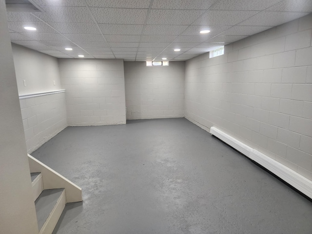 basement with concrete block wall, a paneled ceiling, and recessed lighting