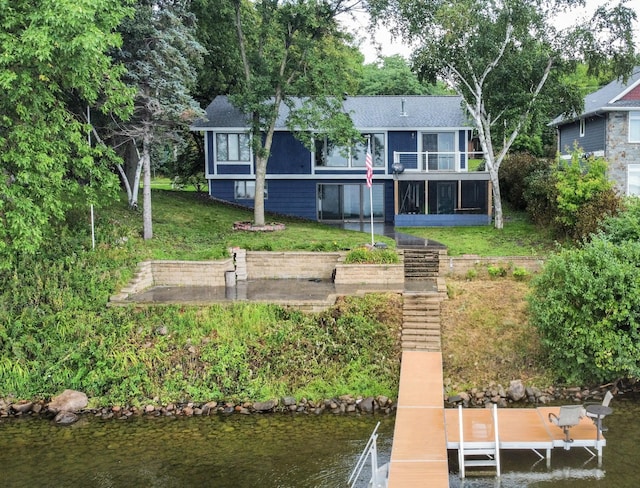 rear view of house with a yard, a sunroom, and a water view