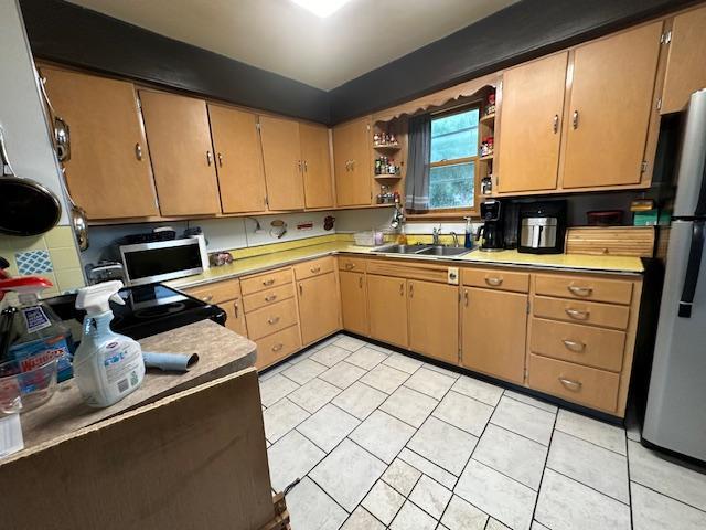 kitchen with light tile patterned flooring, appliances with stainless steel finishes, and sink