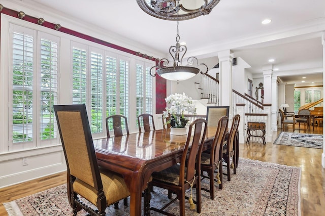 dining room with light wood-type flooring, ornamental molding, and ornate columns