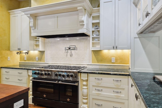 kitchen featuring backsplash, dark stone countertops, premium range hood, and double oven range