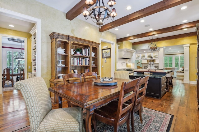 dining area with sink, wood-type flooring, plenty of natural light, and an inviting chandelier