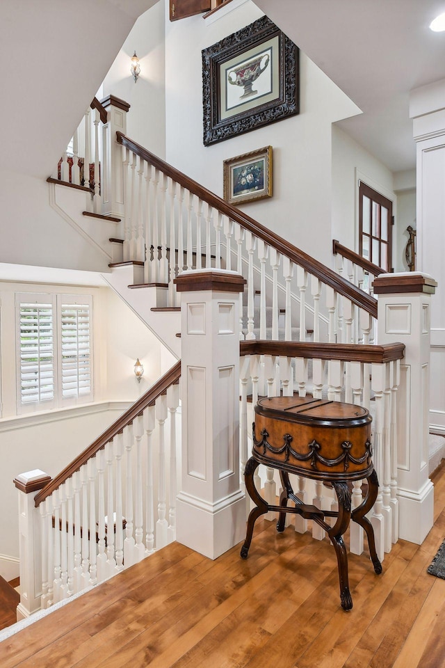 staircase featuring a towering ceiling and wood-type flooring