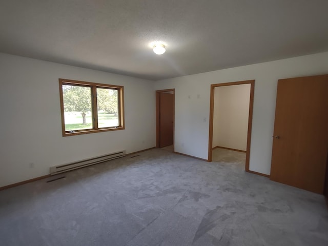 unfurnished bedroom featuring a closet, a baseboard heating unit, and light colored carpet