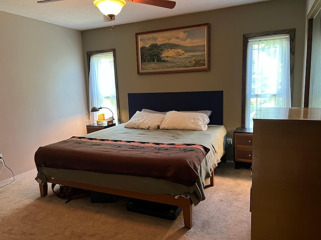 carpeted bedroom with a textured ceiling, ceiling fan, and multiple windows