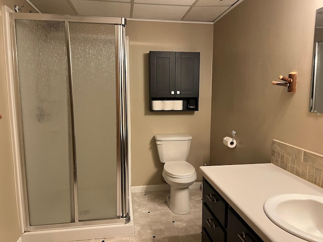 bathroom featuring a shower with door, a paneled ceiling, toilet, vanity, and tile patterned floors