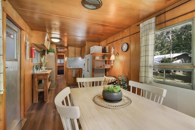 dining room with wood walls, dark wood-type flooring, a healthy amount of sunlight, and wooden ceiling