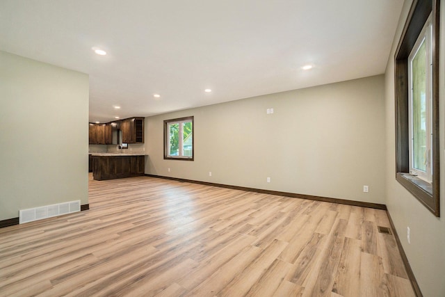 unfurnished living room with light wood-style flooring, visible vents, and baseboards