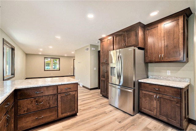 kitchen with light stone counters, stainless steel fridge, and dark brown cabinetry