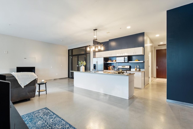 kitchen featuring white cabinets, stainless steel appliances, a chandelier, an island with sink, and pendant lighting