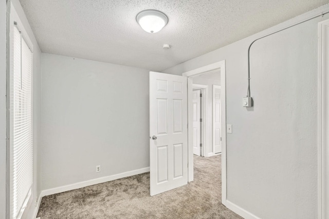 unfurnished bedroom featuring a textured ceiling and light carpet