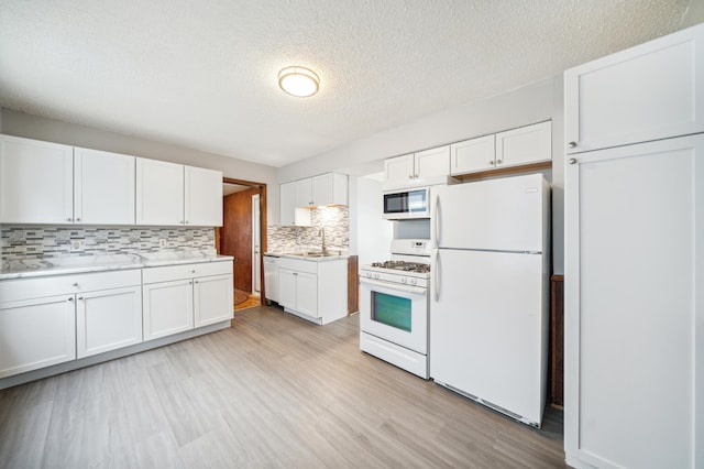 kitchen featuring white cabinets, light wood-type flooring, and white appliances