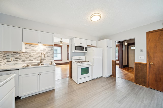 kitchen with light hardwood / wood-style floors, white cabinetry, white appliances, a textured ceiling, and sink