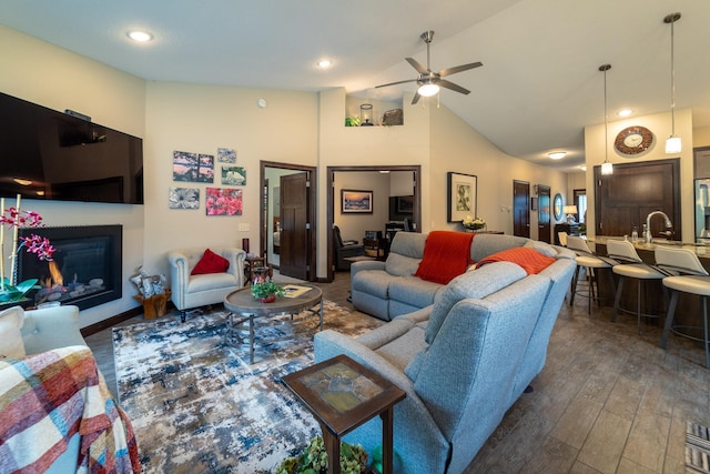 living area featuring a glass covered fireplace, ceiling fan, wood finished floors, high vaulted ceiling, and recessed lighting