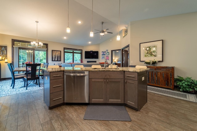 kitchen with a sink, light stone counters, stainless steel dishwasher, and wood finished floors