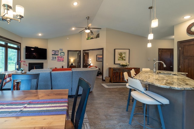 dining room featuring lofted ceiling, recessed lighting, a fireplace, a ceiling fan, and dark wood-style floors