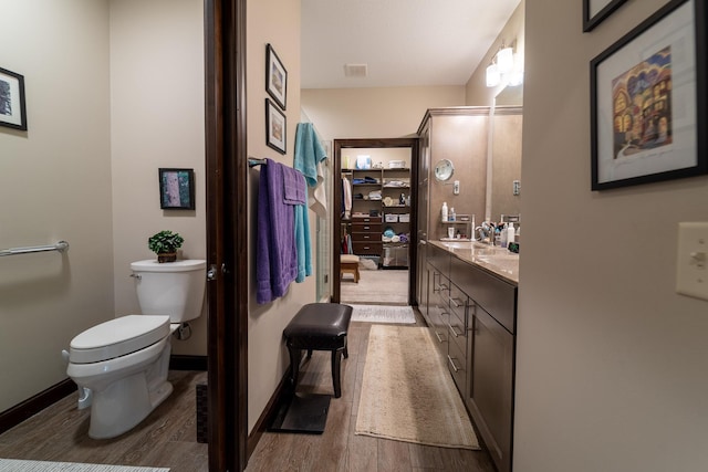 full bath with toilet, wood finished floors, visible vents, vanity, and baseboards