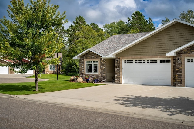 view of front of house with a garage, concrete driveway, stone siding, roof with shingles, and a front lawn