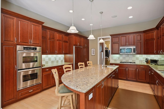 kitchen with a breakfast bar, an island with sink, pendant lighting, stainless steel appliances, and decorative backsplash