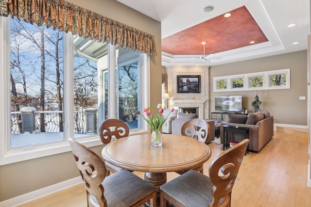 dining room featuring ceiling fan, light hardwood / wood-style floors, and a tray ceiling