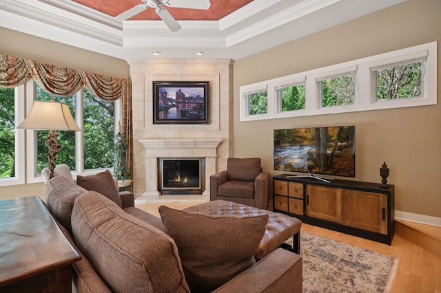 living room featuring crown molding, a fireplace, a tray ceiling, and light hardwood / wood-style floors