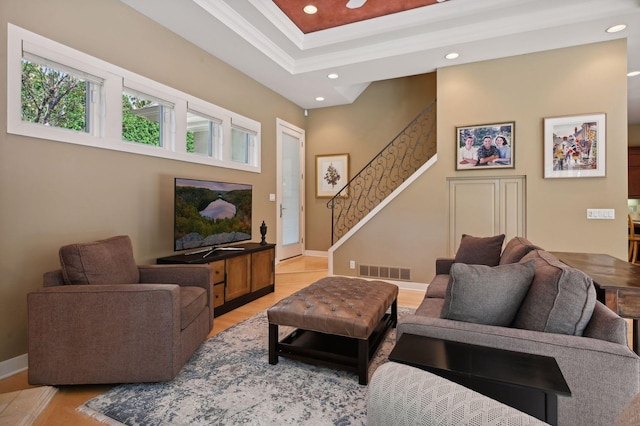 living room with a tray ceiling, ornamental molding, and light hardwood / wood-style floors