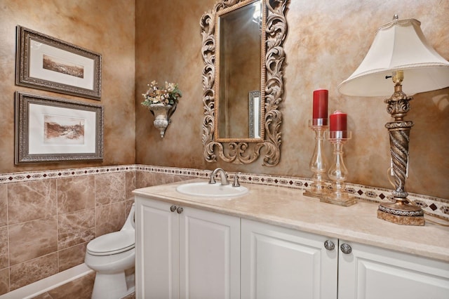 bathroom featuring vanity, toilet, and tile walls