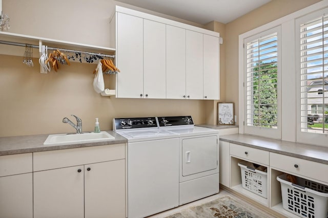 clothes washing area with independent washer and dryer, cabinets, and sink