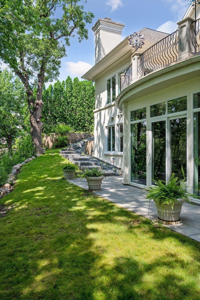 back of house featuring a patio, a balcony, and a lawn