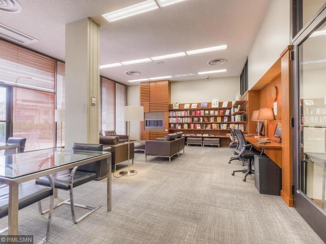 home office with expansive windows, visible vents, and light colored carpet