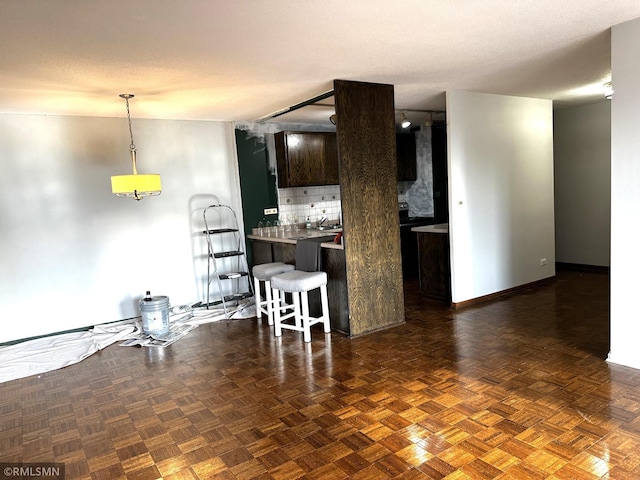 kitchen featuring pendant lighting, light countertops, backsplash, a peninsula, and a kitchen breakfast bar