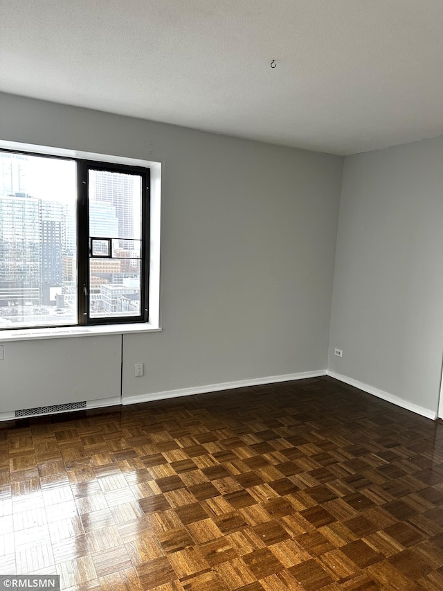 unfurnished room with a textured ceiling, visible vents, and baseboards