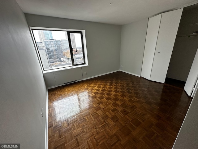 unfurnished bedroom featuring baseboards, a closet, and a city view