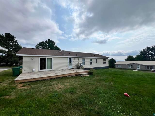 back of property featuring a yard and a wooden deck