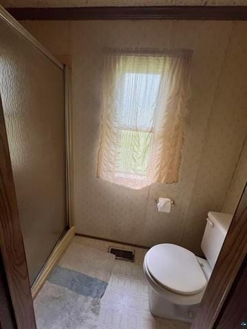 bathroom with a shower with shower door and toilet