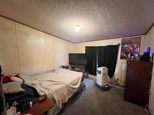 bedroom featuring a textured ceiling and dark carpet