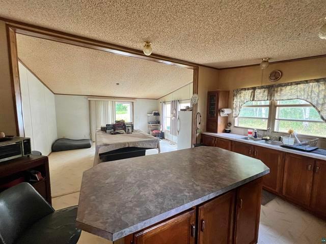 kitchen with sink, crown molding, a textured ceiling, and a center island