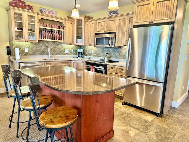 kitchen with appliances with stainless steel finishes, sink, a kitchen island, and a kitchen breakfast bar