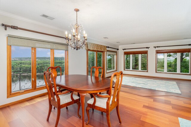 dining space featuring light wood-type flooring, visible vents, crown molding, baseboards, and a chandelier