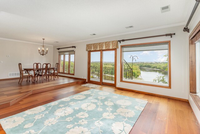 unfurnished living room with a chandelier, crown molding, and light wood-type flooring
